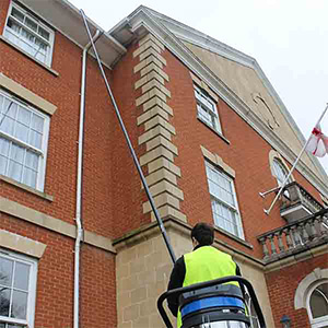 High Reach Cleaning. Man cleaning high gutters from the ground.